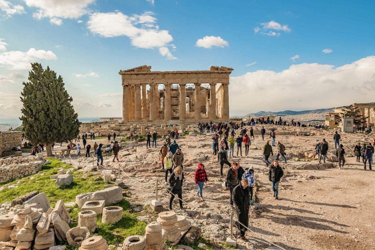 Visitors exploring the ancient ruins of the Parthenon on a sunny day with a clear sky.
